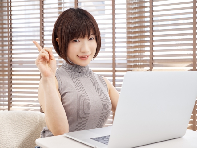 人差し指を上げ注目と言いたげな女性の画像