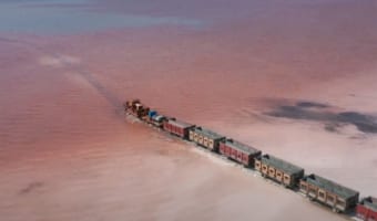 まるでおとぎ話の世界のよう・・・ピンク色の塩湖を貨物列車が横切る光景が話題に!