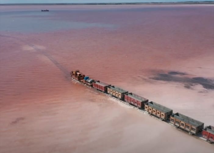 まるでおとぎ話の世界のよう･･･ピンク色の塩湖を貨物列車が横切る光景が話題に！