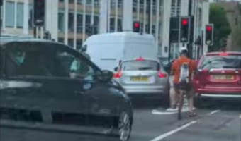 前を行く自転車に乗るライダーに背負われているイヌ。よく見るとその姿がワイルド&クールだった!!