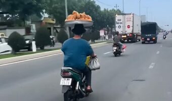 バランス感覚がスゴすぎる!山盛りのドーナツのトレーを頭に乗せて男性がバイクで走っていく!!【海外・動画】