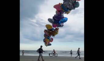 ビーチを歩くバルーン売り。果てしなくつながるバルーンの束が圧巻の映えを生む！【海外・動画】